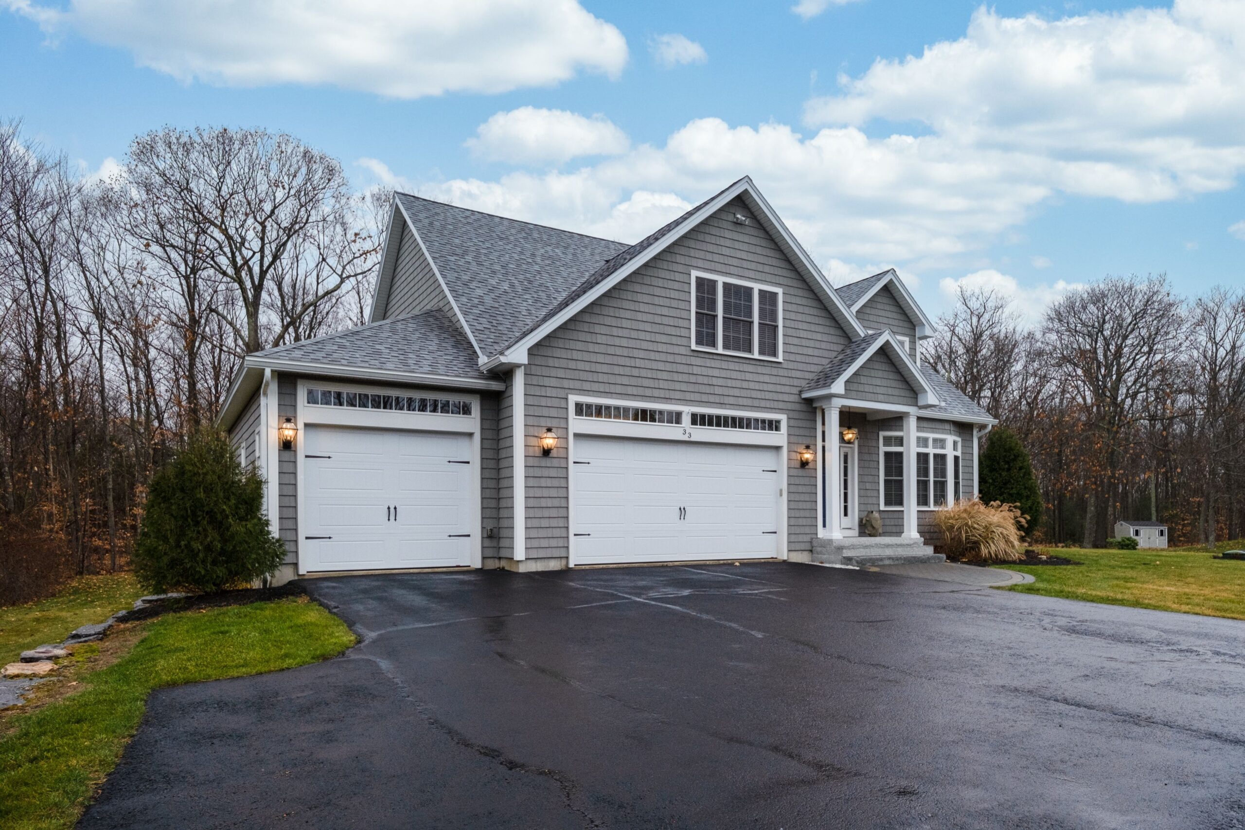 gray walled suburban house with white asphalt driveway